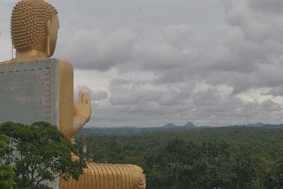 Golden Temple: Buddha and the distant rock of Sigiriya , in Dambulla (Sri Lanka, Cultural Triangle)