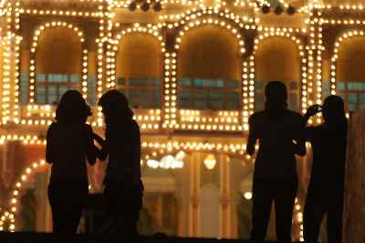 People taking photos in front of Maharaja Palace illuminated for Dasara (Dussera) festival in Mysore, Karnataka, India
